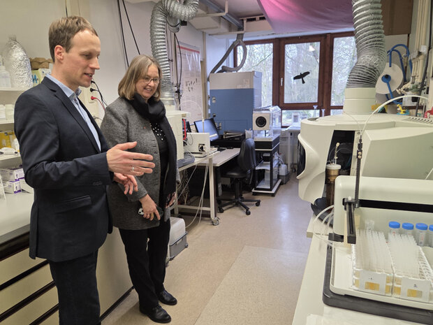 Ein Mann erläutert einer Frau in einem Labor ein wissenschaftliches Gerät.